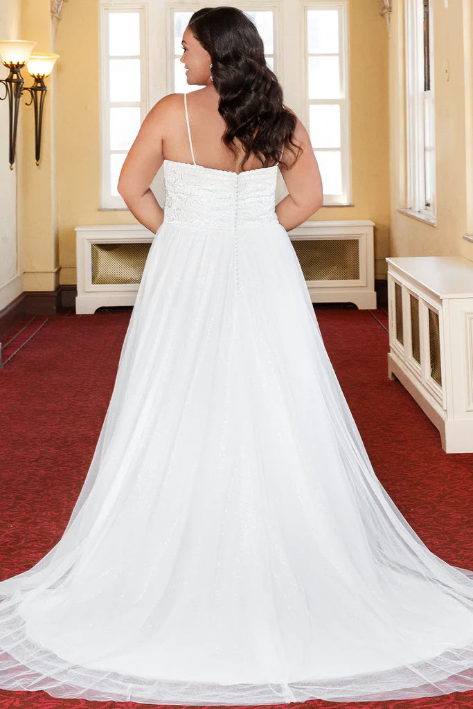 Michelle Bridal For Sydney's Closet MB2318 A-Line Lace Clear Sequins Soft Bridal Tulle Glitter Tulle Lace Trim Satin Plus Size "Coralie" Bridal Gown. The Michelle Bridal For Sydney's Closet MB2318 gown is perfect for the modern plus-size bride seeking a classic look. The A-Line silhouette features a glitter tulle skirt and sheer lace bodice, adorned with soft bridal tulle, clear sequins, and satin trim. Capture timeless elegance in the “Coralie” gown.