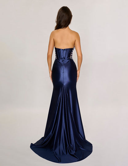 Make a bold entrance with the Nina Canacci 5307 gown. This long, fitted strapless dress features a seductive corset silhouette with sheer panels that hint at allure, while the satin fabric drapes smoothly across your figure. A daring thigh-high slit adds movement and confidence, perfect for unforgettable evenings and prom night glamour.

Size: 0-12

Color: Burgundy, Navy, Emerald