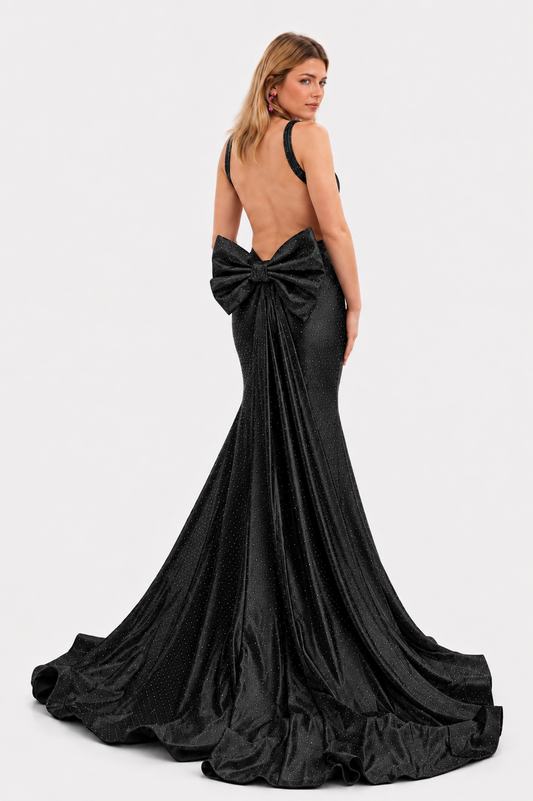 Make a stunning entrance in this Nina Canacci 9212 prom gown, expertly crafted from luxurious crystal-studded jersey. The backless silhouette showcases elegant lines while the detachable oversized bow adds dramatic flair. A removable overskirt transforms the mermaid base into a sophisticated formal statement piece. Perfect for prom, pageants, or black-tie events, this gown combines timeless elegance with contemporary design details that command attention.

Sizes: 2, 8

Colors: Black