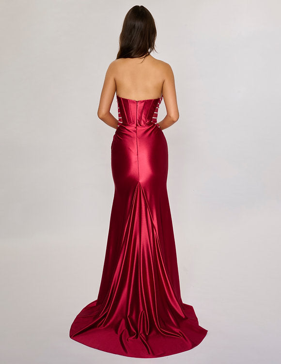 Make a bold entrance with the Nina Canacci 5307 gown. This long, fitted strapless dress features a seductive corset silhouette with sheer panels that hint at allure, while the satin fabric drapes smoothly across your figure. A daring thigh-high slit adds movement and confidence, perfect for unforgettable evenings and prom night glamour.

Size: 0-12

Color: Burgundy, Navy, Emerald