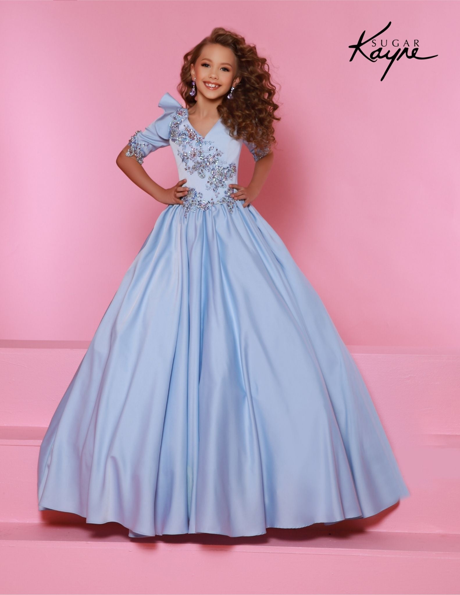 This beautiful Sugar Kayne C343 Pageant Dress offers a stunning A-line silhouette with a unique plunging V neckline adorned with dazzling crystals. Crafted from luxurious satin fabric, this dress is perfect for the little girl who wants to shine. Embrace the glamour of a storybook princess. Our Stretch Crepe Back Satin ballgown is sure to radiate grace of a true princess!