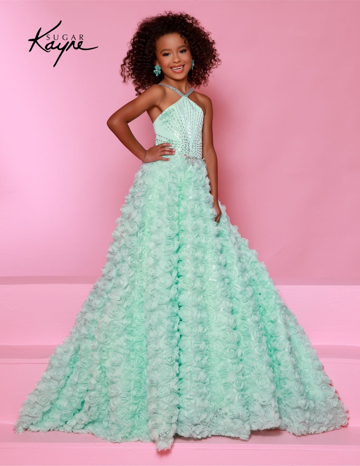 This Sugar Kayne C351 dress will make any girl feel like a princess. It features a delicate 3D rose mesh ballgown with a halter neckline and an A-line silhouette, perfect for preteen pageants. The fine detailing and quality materials ensure that this dress will turn heads and make your girl feel special. Petals of perfection – our 3D Rose Mesh Ballgown featuring a halter neckline is designed to make you shine on stage with elegance and grace!