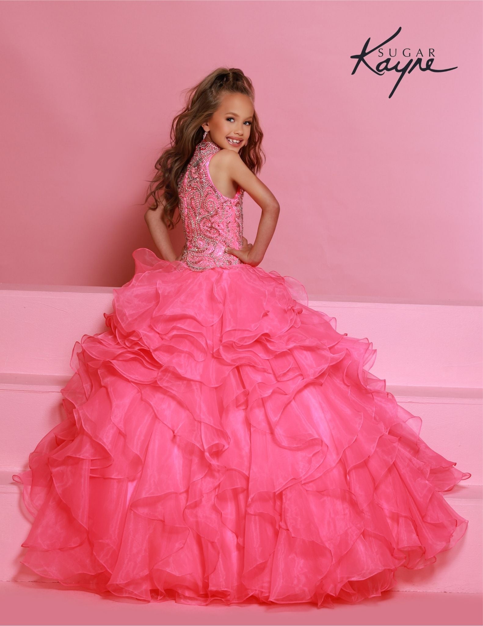 Sugar Kayne C326 Barbie Pink is the perfect pageant dress for young girls and preteens, featuring a ruffled long skirt, high neckline, and crystal bodice with sleeveless design.