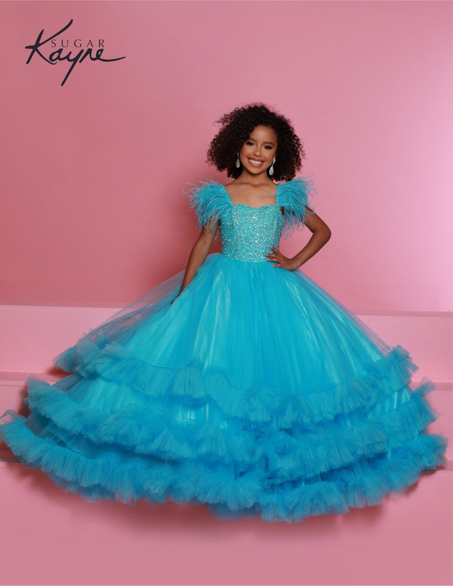Sugar Kayne C327 features a fashionable aqua pageant dress for girls and preteens, complete with feather straps, a tiered ruffle bottom, and a crystal stone bodice.