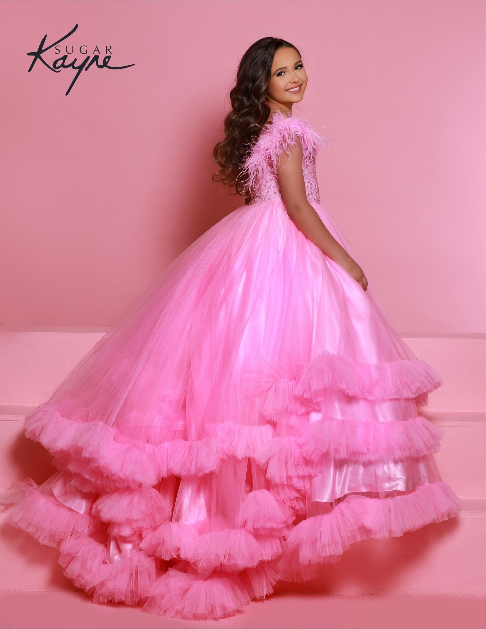 Sugar Kayne C327 features a fashionable bubblegum pageant dress for girls and preteens, complete with feather straps, a tiered ruffle bottom, and a crystal stone bodice.