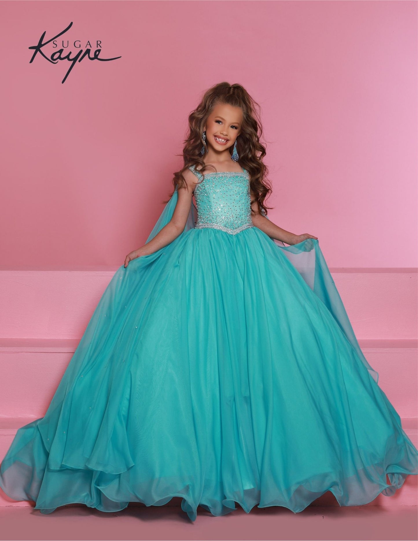 Sugar Kayne C329 Ocean Pageant Dress features a chiffon skirt, semi sweetheart neckline encrusted with rhinestones and wide straps with a cape.