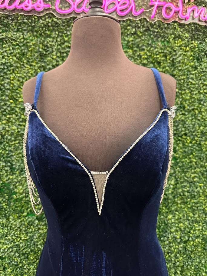 This Johnathan Kayne 2706 gown features a long fitted velvet silhouette with a pleated mermaid skirt and elegant train, designed to enhance your figure with sophisticated flair. The off-the-shoulder sleeves are adorned with a detachable crystal fringe tassel, adding a touch of sparkle and versatility. Perfect for pageants or formal events, This velvet dress combines classic elegance with modern detailing for a standout look.

Size: 4

Color: Navy/Aqua