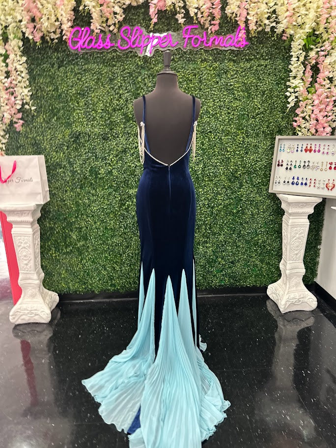 This Johnathan Kayne 2706 gown features a long fitted velvet silhouette with a pleated mermaid skirt and elegant train, designed to enhance your figure with sophisticated flair. The off-the-shoulder sleeves are adorned with a detachable crystal fringe tassel, adding a touch of sparkle and versatility. Perfect for pageants or formal events, This velvet dress combines classic elegance with modern detailing for a standout look.

Size: 4

Color: Navy/Aqua