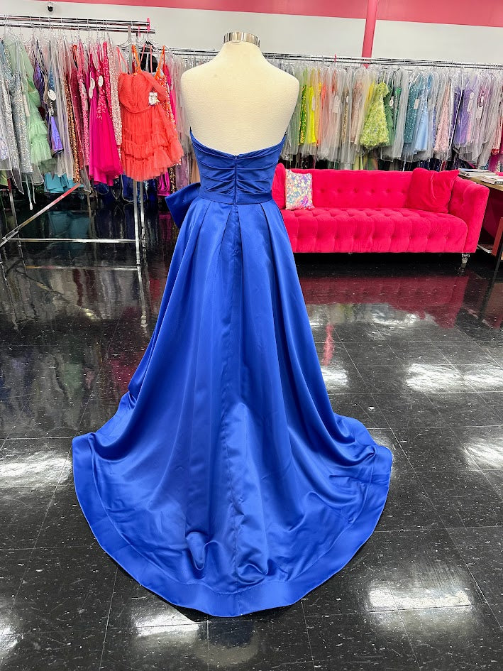 Discover elegance and glamour with the Candice Wang 72499 Royal Satin Maxi Slit A Line Bow Prom Dress. This stunning formal dress features a crystal-embellished V-neck and a gorgeous bow detail. With its A-line silhouette and thigh-high slit, it's perfect for any pageant or prom.&nbsp;

Sizes: 8

Colors: Royal