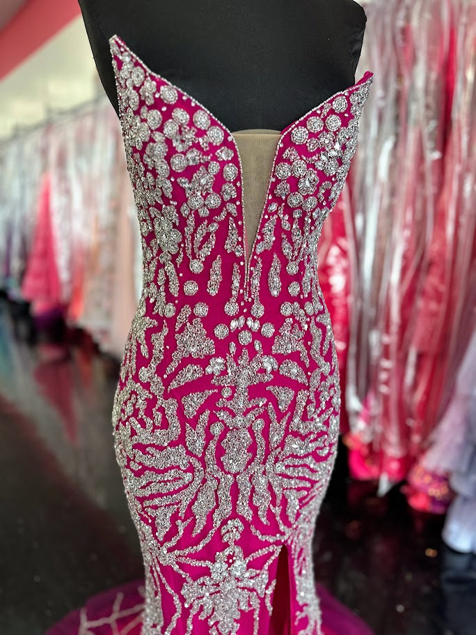 This elegant fuchsia evening gown from Chic and Holland features intricate beadwork that enhances its sophisticated appeal. Designed for formal occasions, the floor-length dress includes a tasteful slit, offering both movement and modern style. Tailored to a size 2, it delivers a flattering silhouette perfect for pageants or upscale events. The combination of refined detailing and vibrant color ensures a standout presence at any formal gathering.

Size: 2

Colors: Fuchsia