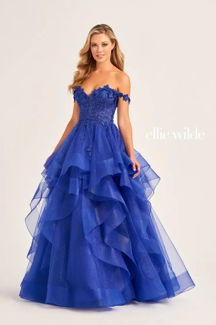 Make a statement in the Ellie Wilde EW35084 prom dress. Featuring an off-the-shoulder top, shimmer sequin lace and ruffle detail, the dress offers a timeless and sophisticated look perfect for the big night. Keep it classic in this classic formal gown.  Sizes: 00-24  Colors: EMERALD, ROYAL BLUE, TEAL, HOT PINK, BLUEBELL