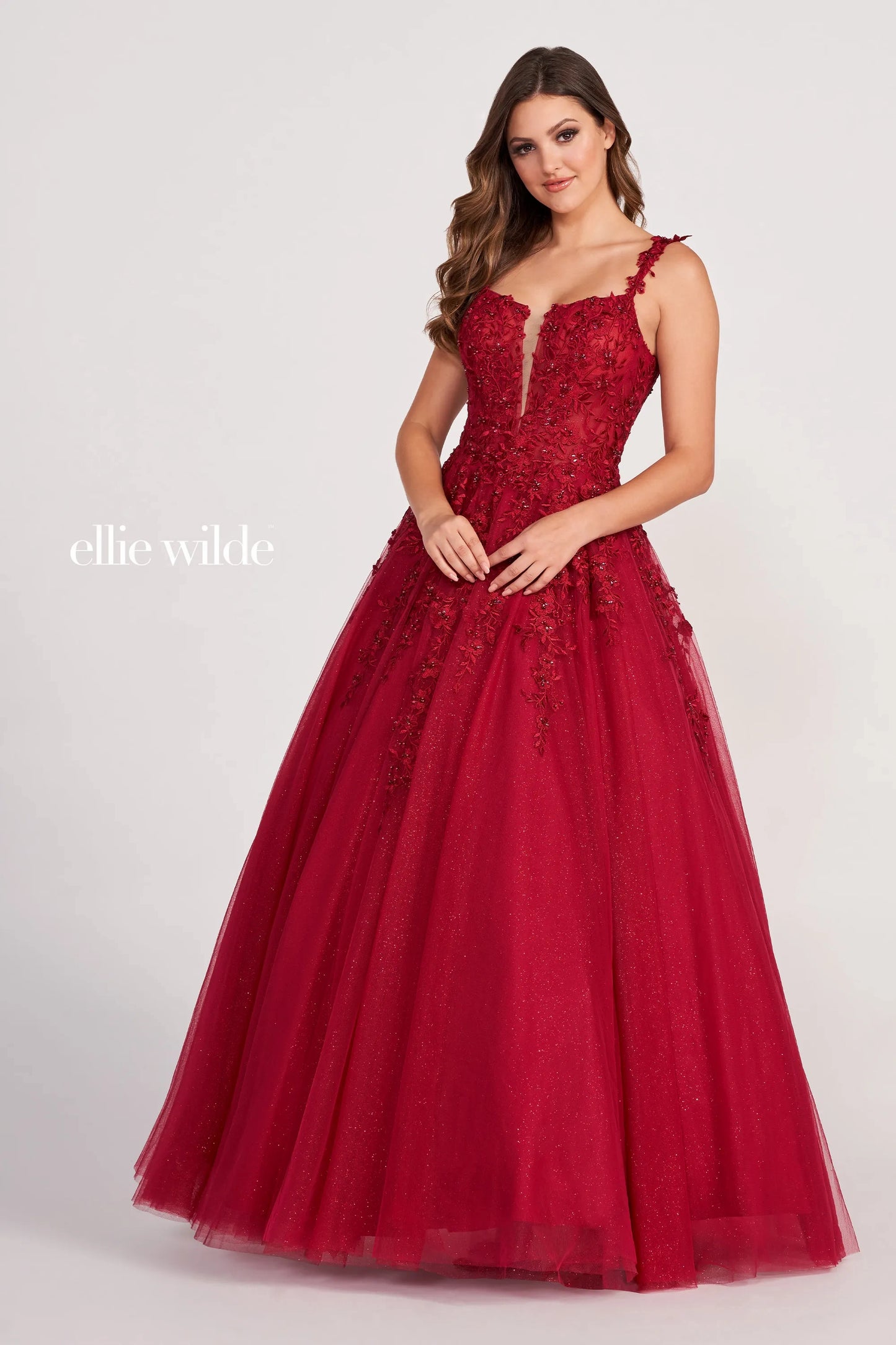 Introducing the Ellie Wilde EW120014 Long Sheer Lace Shimmer Ballgown. This sophisticated formal gown features a sheer bodice with tulle and lace appliqué, an A-line silhouette, plunging V-neckline and natural waist for a flattering fit. The skirt flows to the floor for an airy and graceful look. Make a lasting impression at your prom or special occasion.  Sizes: 00-24  Colors: PERIWINKLE, LAVENDER, RED, ROSE QUARTZ, ROYAL BLUE, WINE, TEAL, WHITE, EMERALD, NAVY BLUE, BLACK, PEONY
