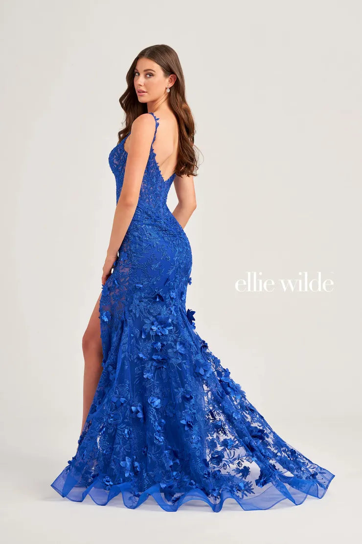 Elevate your prom look with Ellie Wilde EW35053 sheer lace shimmer gown. Featuring a mermaid silhouette, scoop neck, and a daring leg slit, this dress is sure to turn heads. With its intricate lace detailing and shimmering fabric, you'll feel like a princess on your special night. Covered in heat set crystals and beading.  Sizes: 00-16  Colors: Royal Blue, Black, Red