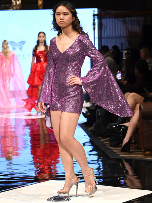This Marc Defang 8219 Sequin Long Bell Sleeve Pageant Romper is designed with an eye-catching sequin pattern, long bell sleeves and a modern fit. It's the perfect choice for formal events, offering show-stopping style and comfort. contact us for additional colors  Sizes: 00-16  Colors: Lilac, Eggplant, Purple, Blue