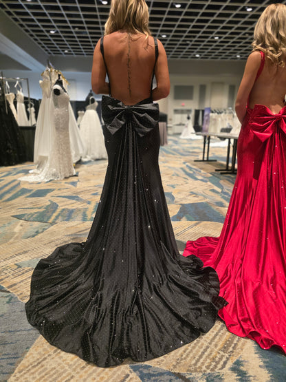 Make a stunning entrance in this Nina Canacci 9212 prom gown, expertly crafted from luxurious crystal-studded jersey. The backless silhouette showcases elegant lines while the detachable oversized bow adds dramatic flair. A removable overskirt transforms the mermaid base into a sophisticated formal statement piece. Perfect for prom, pageants, or black-tie events, this gown combines timeless elegance with contemporary design details that command attention.

Sizes: 0-14

Colors: Sky Blue, Red, Black
