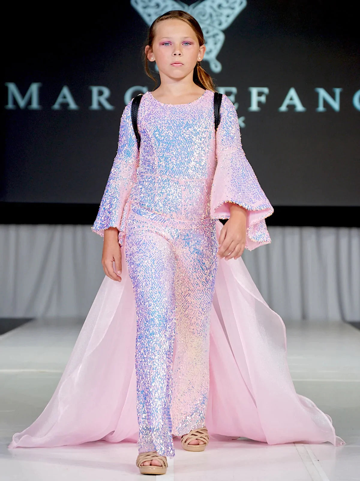 Marc Defang 8004K Sequin Bell Sleeve Pageant Jumpsuit Overskirt Fun Fashion   Price is inclusive of overskirt  Fully beaded jumpsuit Bell sleeve Option of matching overskirt Knitted inner comfort lining  Available Sizes: 4-14  Available Colors: Baby Pink, Light Purple, Light Orange, Mint
