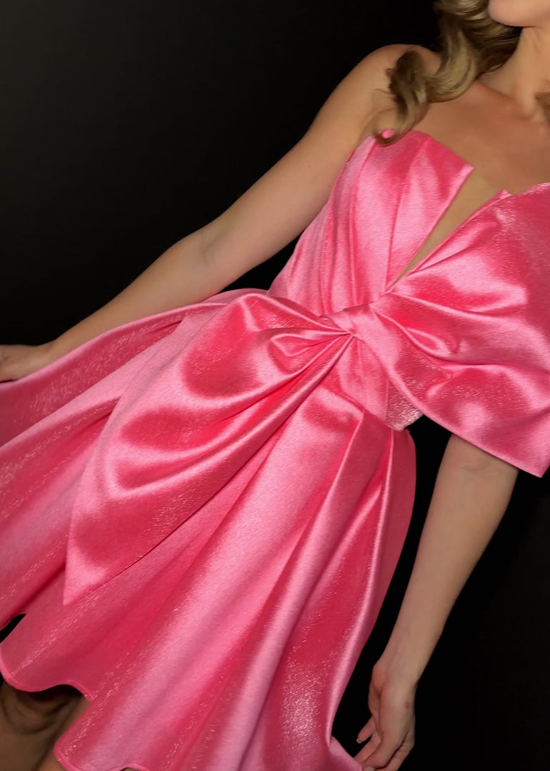 Elevate your formal occasion with the Ashley Lauren 4816 cocktail dress, featuring a flattering short fit and flared silhouette. The elegant pleated design is complemented by an oversized bow, adding a refined touch to the V-neck neckline. Perfect for homecoming or any special event, this dress combines classic sophistication with modern charm for a truly memorable look. ASHLEYlauren Style 4816 is a short Mikado dress that combines playful charm with bold sophistication. Featuring a structured bodice and ov