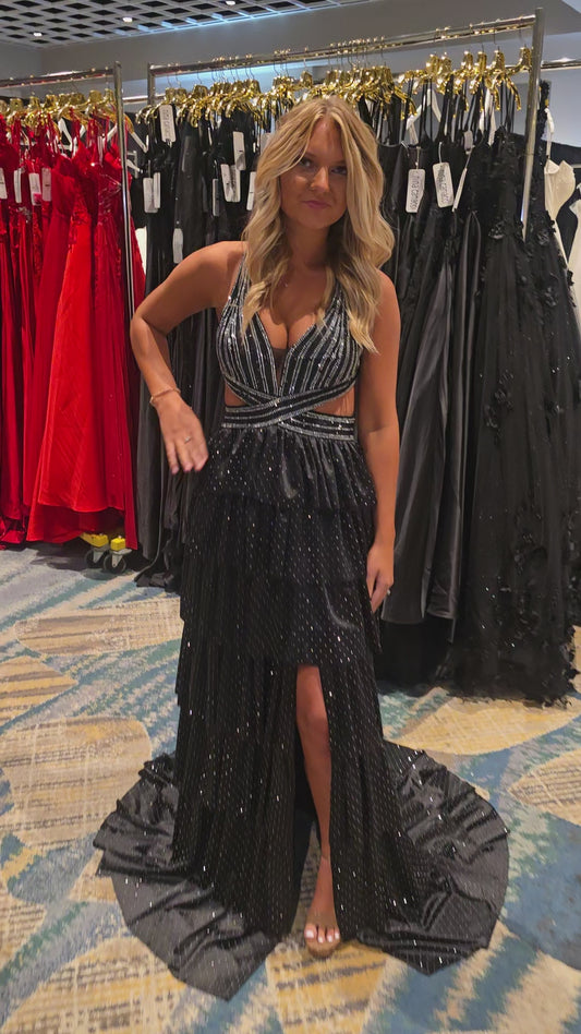Nina Canacci's 9200 is a show-stopping pageant gown that combines elegance with contemporary flair. The crystal-layered jersey skirt features intricate micro crystal embellishments that catch light beautifully, while strategic side cutouts add modern sophistication. A dramatic maxi slit and flowing train create movement and grandeur, making this dress ideal for prom, pageants, and formal competitions. The jersey construction ensures comfortable wear throughout the evening while maintaining a polished silhou