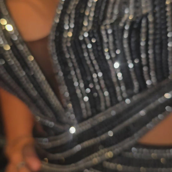 Nina Canacci's 9200 is a show-stopping pageant gown that combines elegance with contemporary flair. The crystal-layered jersey skirt features intricate micro crystal embellishments that catch light beautifully, while strategic side cutouts add modern sophistication. A dramatic maxi slit and flowing train create movement and grandeur, making this dress ideal for prom, pageants, and formal competitions. The jersey construction ensures comfortable wear throughout the evening while maintaining a polished silhou