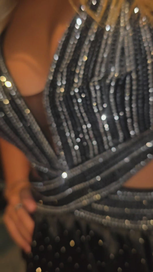 Nina Canacci's 9200 is a show-stopping pageant gown that combines elegance with contemporary flair. The crystal-layered jersey skirt features intricate micro crystal embellishments that catch light beautifully, while strategic side cutouts add modern sophistication. A dramatic maxi slit and flowing train create movement and grandeur, making this dress ideal for prom, pageants, and formal competitions. The jersey construction ensures comfortable wear throughout the evening while maintaining a polished silhou