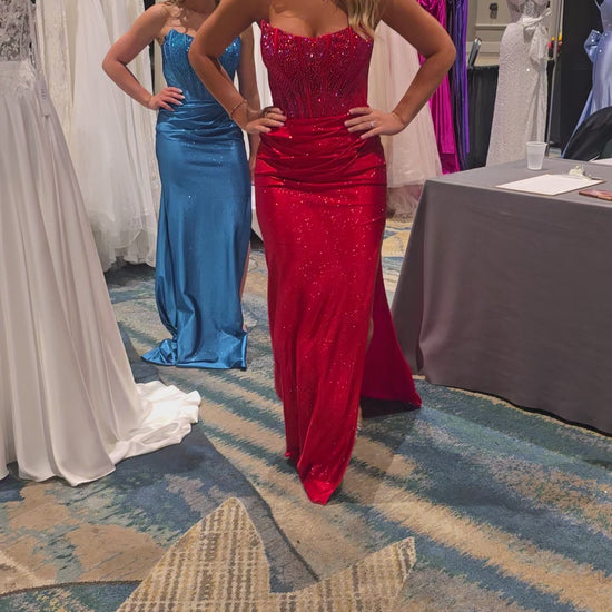 Elevate your prom night with the Nina Canacci style 1605 Crystal Corset Prom Dress. This stunning formal gown features a sheer crystal-embellished corset bodice that commands attention, paired with a luxuriously ruched jersey skirt. The strapless design showcases a graceful scoop neckline, while a dramatic side slit adds movement and sophistication. Perfect for those seeking timeless elegance with modern glamour.

Sizes: 0-10

Colors: Red, Teal, Black