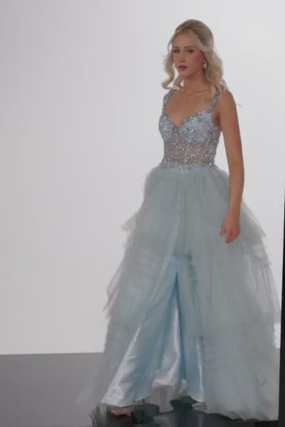 The Jovani 37438 is a captivating prom dress designed for the formal collection, guaranteed to make a grand statement on your prom night. This dress is constructed from tulle, a delicate and ethereal fabric that adds a touch of whimsy and grace to your look. The dress is styled as a classic ballgown, which creates a timeless and elegant silhouette, perfect for special occasions like prom. It features a layered skirt with a slit, adding a hint of drama and allure while allowing for ease of movement. 