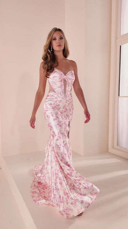 Ellie Wilde's EW37092 is a sophisticated prom dress that combines timeless elegance with contemporary design. Crafted from luxurious satin, this strapless gown features a striking floral print that adds visual interest and dimension. The fitted bodice showcases a dramatic cut-out corset detail that creates an alluring focal point, while the fit-and-flare silhouette with a thigh-high slit offers both flattering structure and graceful movement. Perfect for prom, formal events, or special occasions where you w