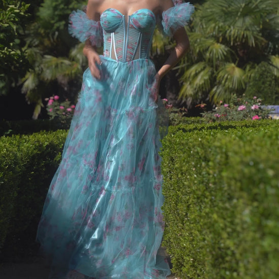 This stunning prom dress by Andrea & Leo Couture features a beautiful floral print, a sheer corset bodice for a touch of sensuality, and a flattering A-line silhouette. The puff sleeves and V-neckline add a touch of romance to this elegant design. Perfect for any special occasion, this dress is sure to make you feel confident and beautiful. Step into a dream with this off-the-shoulder floral printed tulle A-line dress—a whimsical ode to the enchanting world of cottage core
