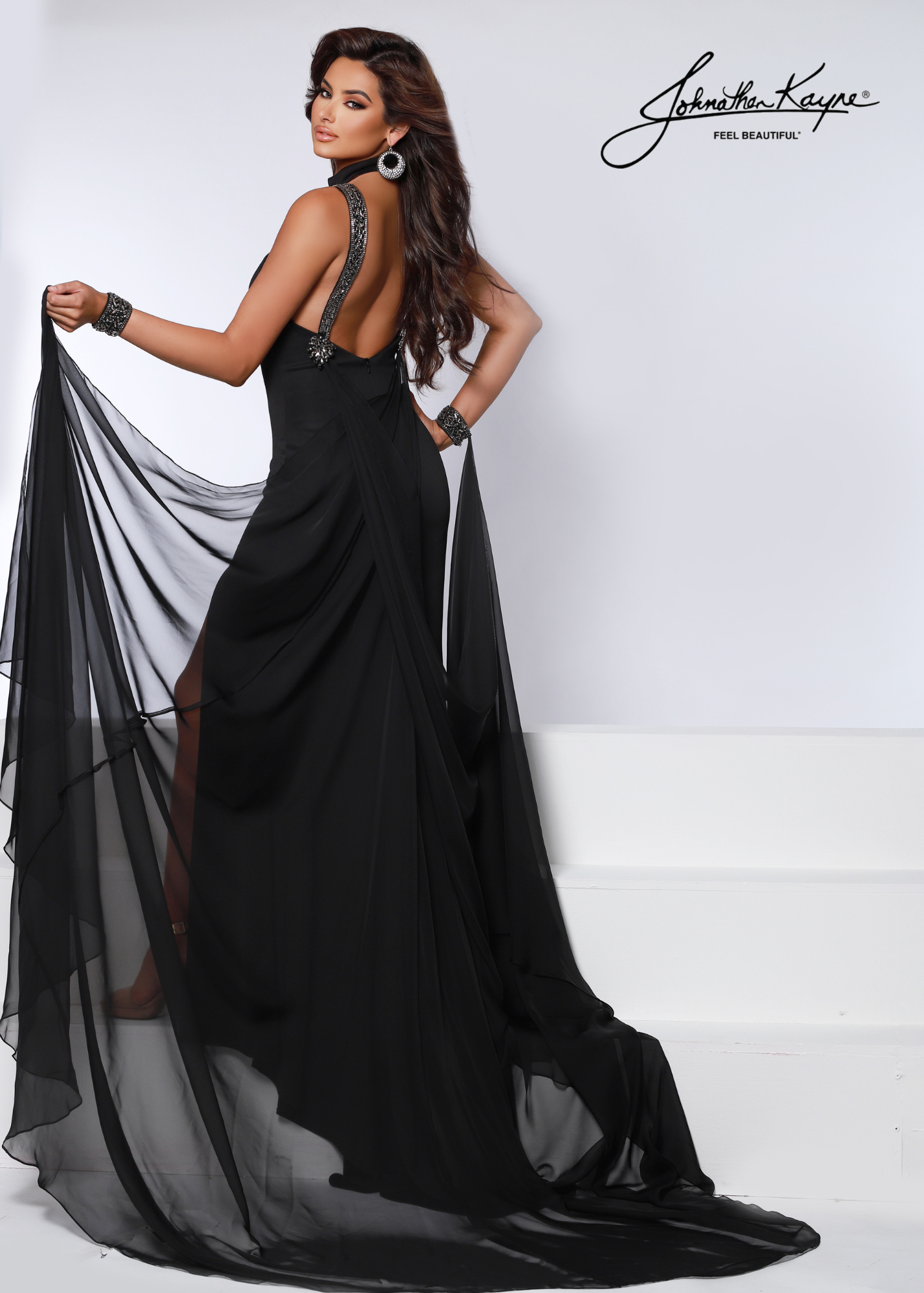 Be a showstopper in this Johnathan Kayne 2617 long slit formal dress! Featuring a breathtaking crystal cuff cape, this pageant gown offers the perfect combination of luxury and glamor for special occasions. Get ready to make a statement and turn heads! #runwayready Look divine in this classy heavy knit beauty! The beaded collar and straps is accompanied by a detachable flowing poly chiffon cape with beaded wrist cuffs.  Colors: Royal, Black, White, Red  Sizes: 00-18
