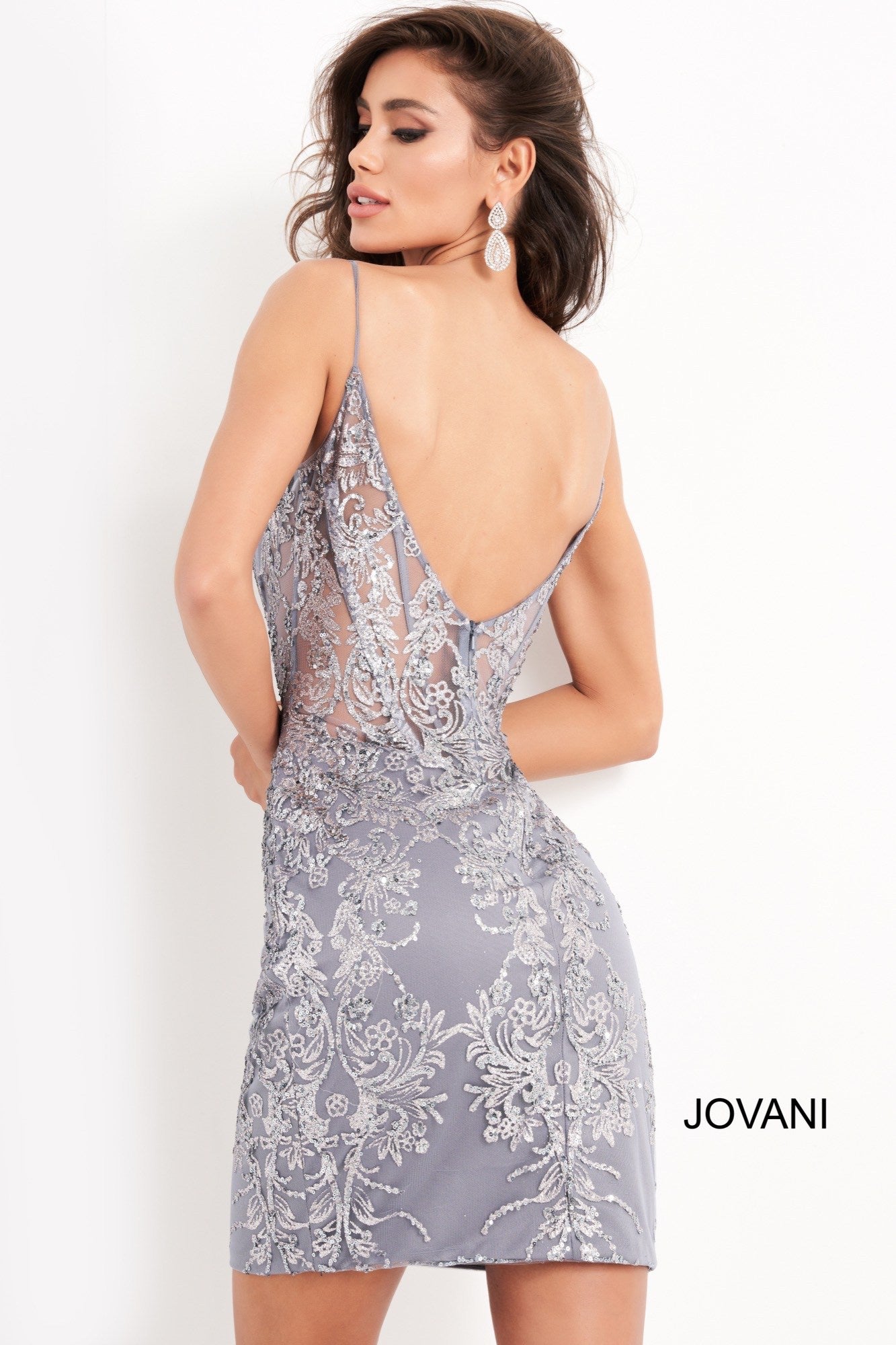 Jovani 04699 is a short fitted formal cocktail evening dress. Great for Prom, Pageants, Homecoming & More! This Gown Features a Sheer Corset Fitted Bodice with boning and a plunging neckline. Open scoop back with sheer panel and tulle spaghetti straps. The entire gown is Embellished with petite sequins and Glitter in a floral scroll pattern. Glass Slipper Formals
