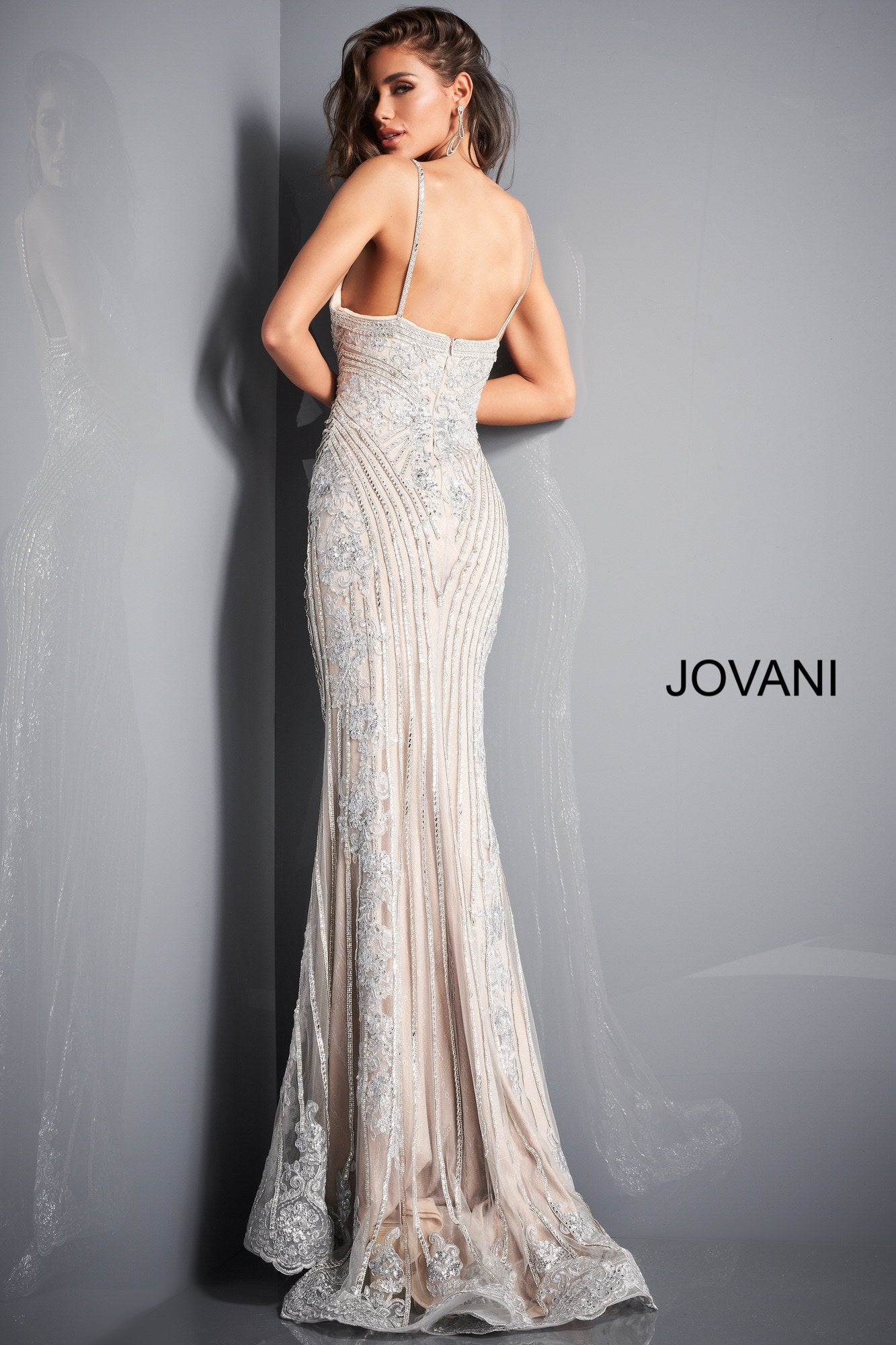 Jovani 05752 This is a silver and nude long mermaid prom dress with embellished lace throughout the evening gown.  It has a v neckline and spaghetti straps. Colors: Silver Nude  Sizes  00-24 