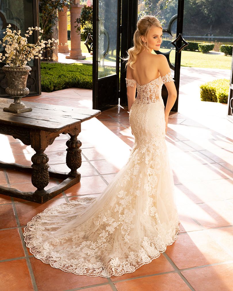 Style 2376 KARINA by Casablanca Bridal is a glamorous twist on the classic lace wedding dress. Off-shoulder sleeves transition into a classic sweetheart neckline, while floral lace swirls all throughout the fit-and-flare silhouette. The illusion back, lined with a row of subtle crystal buttons, transitions flawlessly into a gently scalloped train. A matching, two-tier cathedral length veil is available for the bride who wants to make an extra remarkable impact.  Size: 10, 14, 20  Ivory/Nude/Ivory/Silver