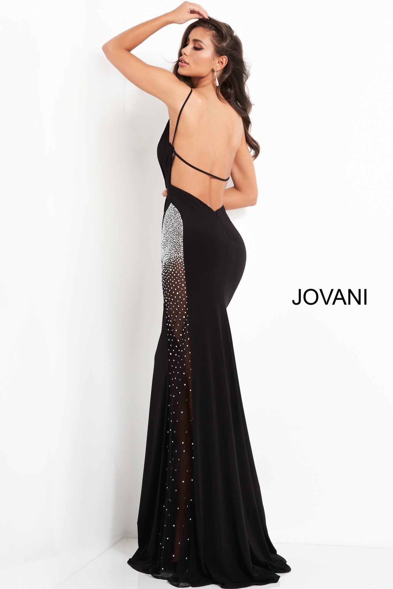 Jovani 06566 is a long fitted formal evening gown. Featuring a deep V Neckline with spaghetti straps and an open back. Sheer side panel on skirt has crystal rhinestones along the hip area dispersing as it flows down the skirt. Great Red Carpet Sexy Black Dress. Available Sizes: 00,0,2,4,6,8,10,12,14,16,18,20,22,24  Available Colors: Black, Light Blue, Red