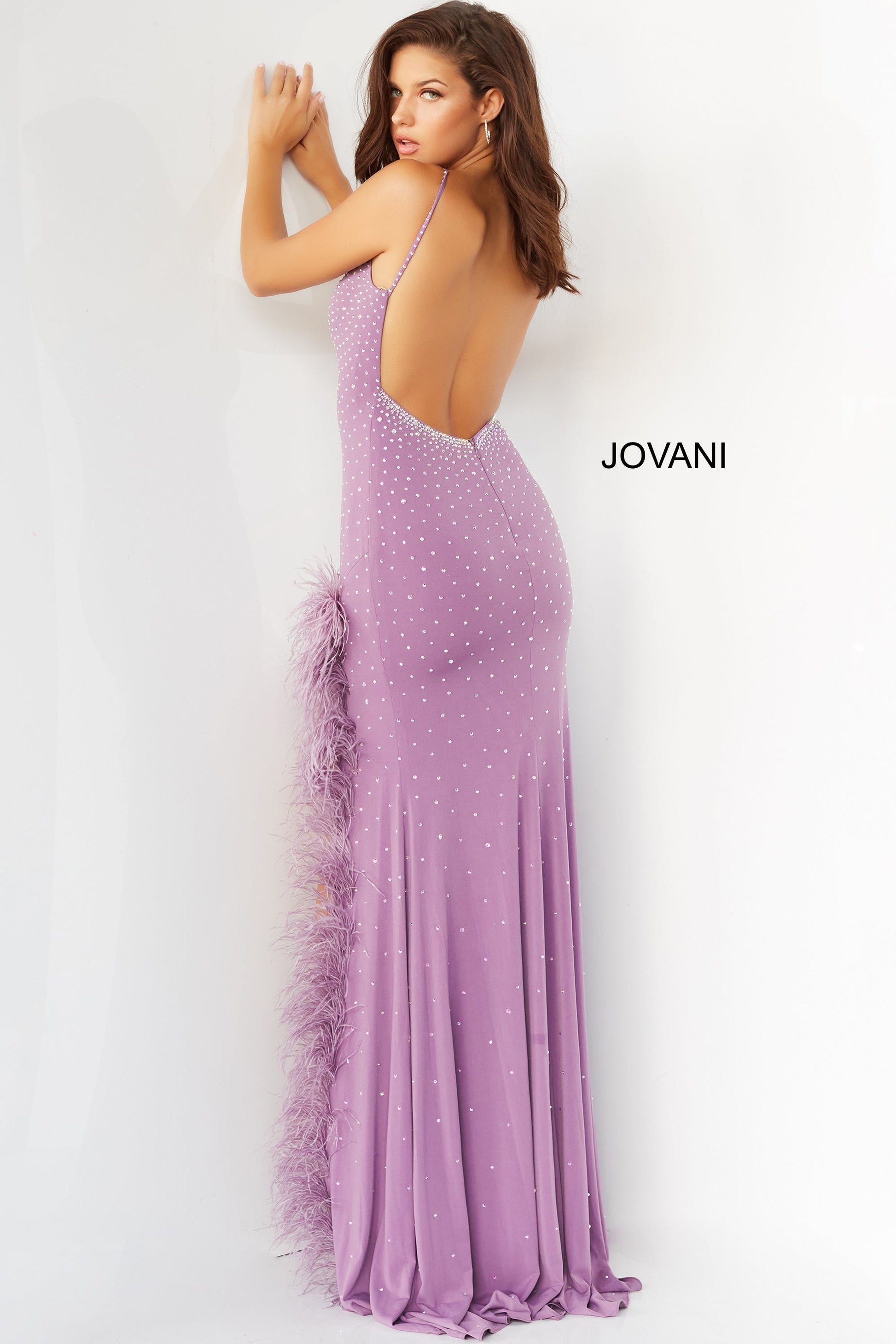 Jovani 08283  Prom, Pageant and Formal Evening Wear Dress.  This extravagant evening gown has a v neckline and low back.  It is fitted and beaded with a feather trimmed slit. Make a statement in this stand out prom dress lilac back