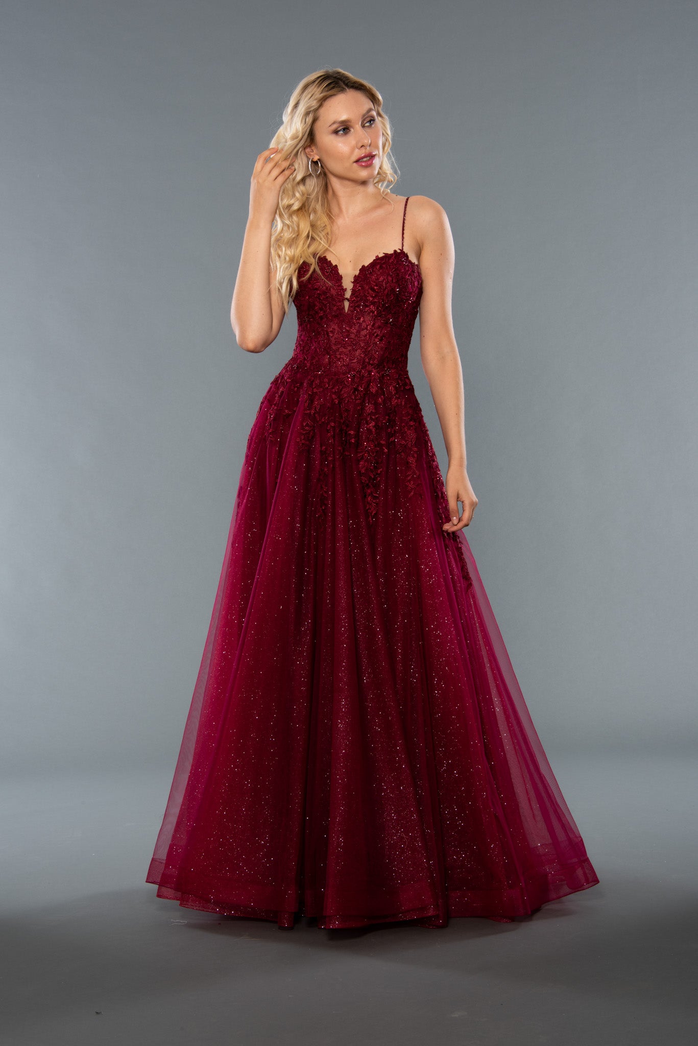 Stella Couture 22027 is an a line with a shimmer tulle ballgown skirt. Fitted sheer corset style lace bodice with plunging neckline. spaghetti straps. Available Sizes: 2-18  Available Colors: Green, Burgundy