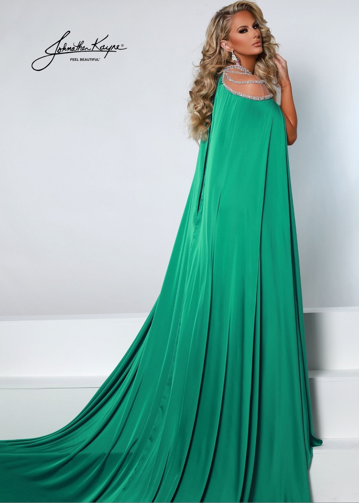 Johnathan Kayne 2535 Long Fitted Velvet Pageant Dress Cape Sheer Crystal Prom Gown A true showstopper! This velvet gown with high neck mesh bodice and sewn in charmeuse skirt will flow across your next pageant stage.  Colors: Emerald, Royal, Black  Sizes: 00, 0, 2, 4, 6, 8, 10, 12, 14, 16, 18  Fabric Stretch Velvet, Stretch Lining