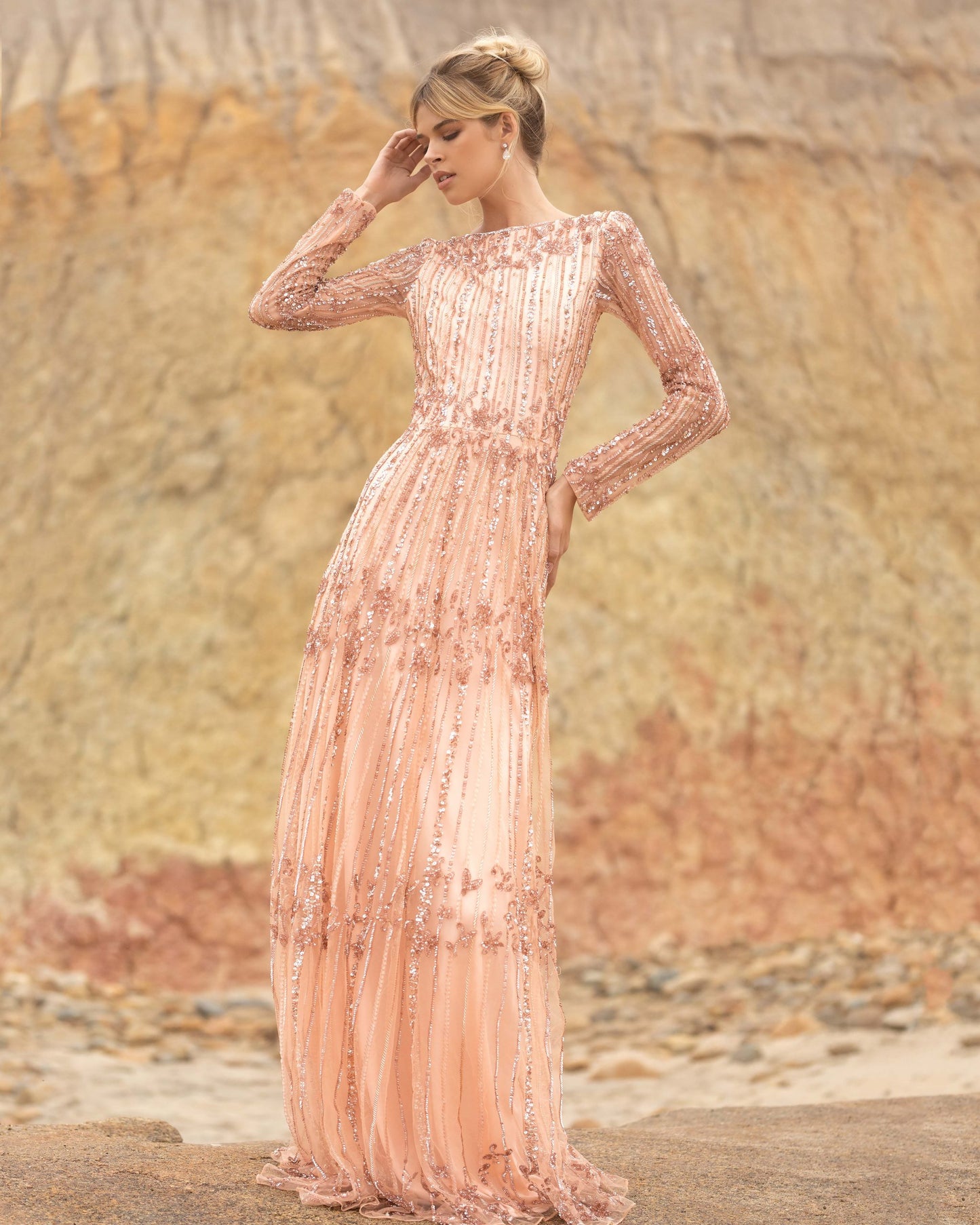 Primavera Couture 3685 This long beaded evening gown has a bateau neckline and long embellished sleeves.  The A line design is beaded to the floor and has a boho tone. Available colors:  Champagne, Black Multi  Available sizes:  0-24