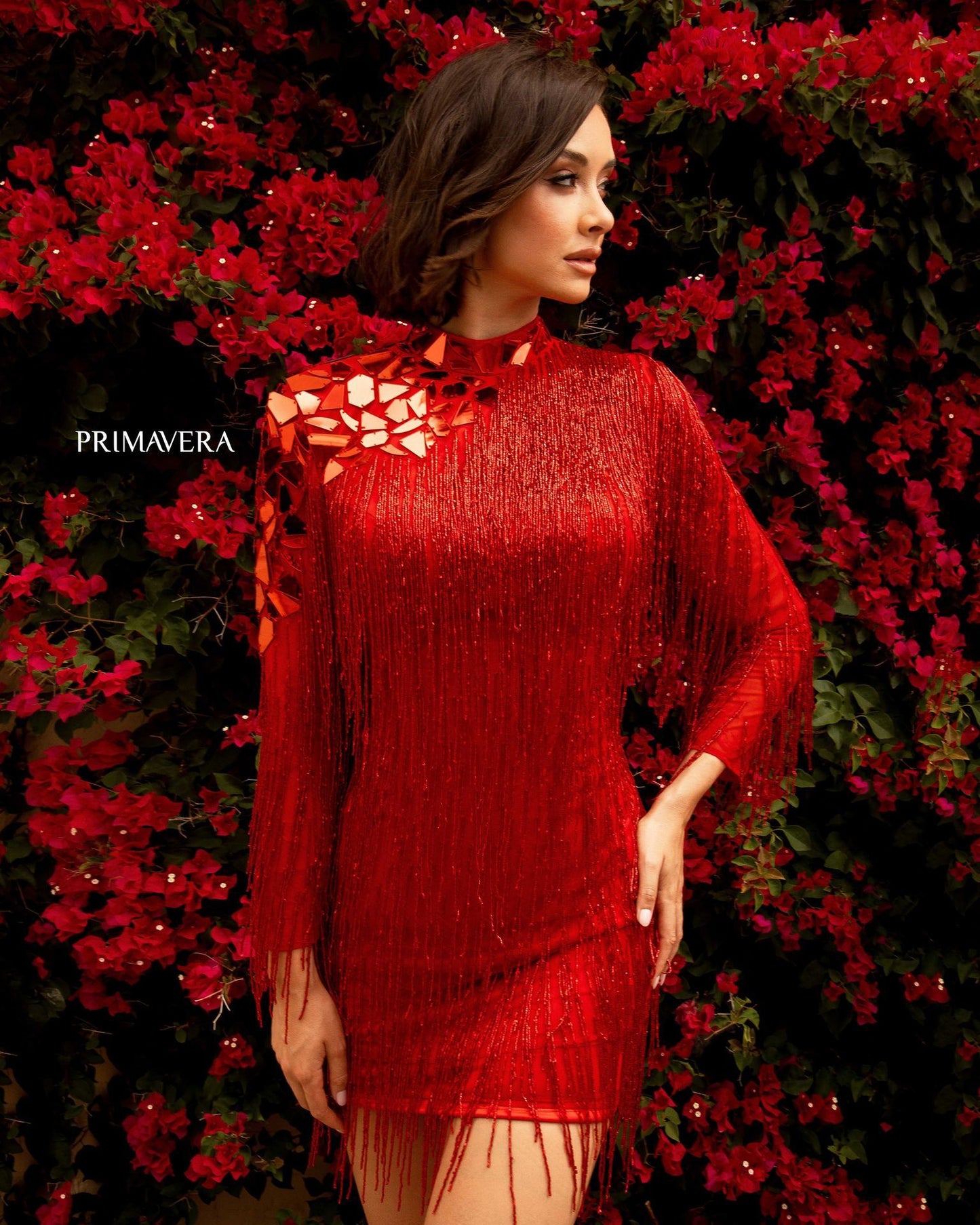 Primavera Couture 3701 is a Show Stopper! This short formal cocktail evening gown is red carpet ready with sheer long sleeves and a high neckline. Featuring hand beaded Fringe tassels along the entire gown and sleeves. high neckline with accented cut glass inspired pieces along the neck and shoulder. open cutout back. This gown has it all!  Available Sizes: 00,0,2,4,6,8,10,12,14,16,18  Available Colors: Blue, Red