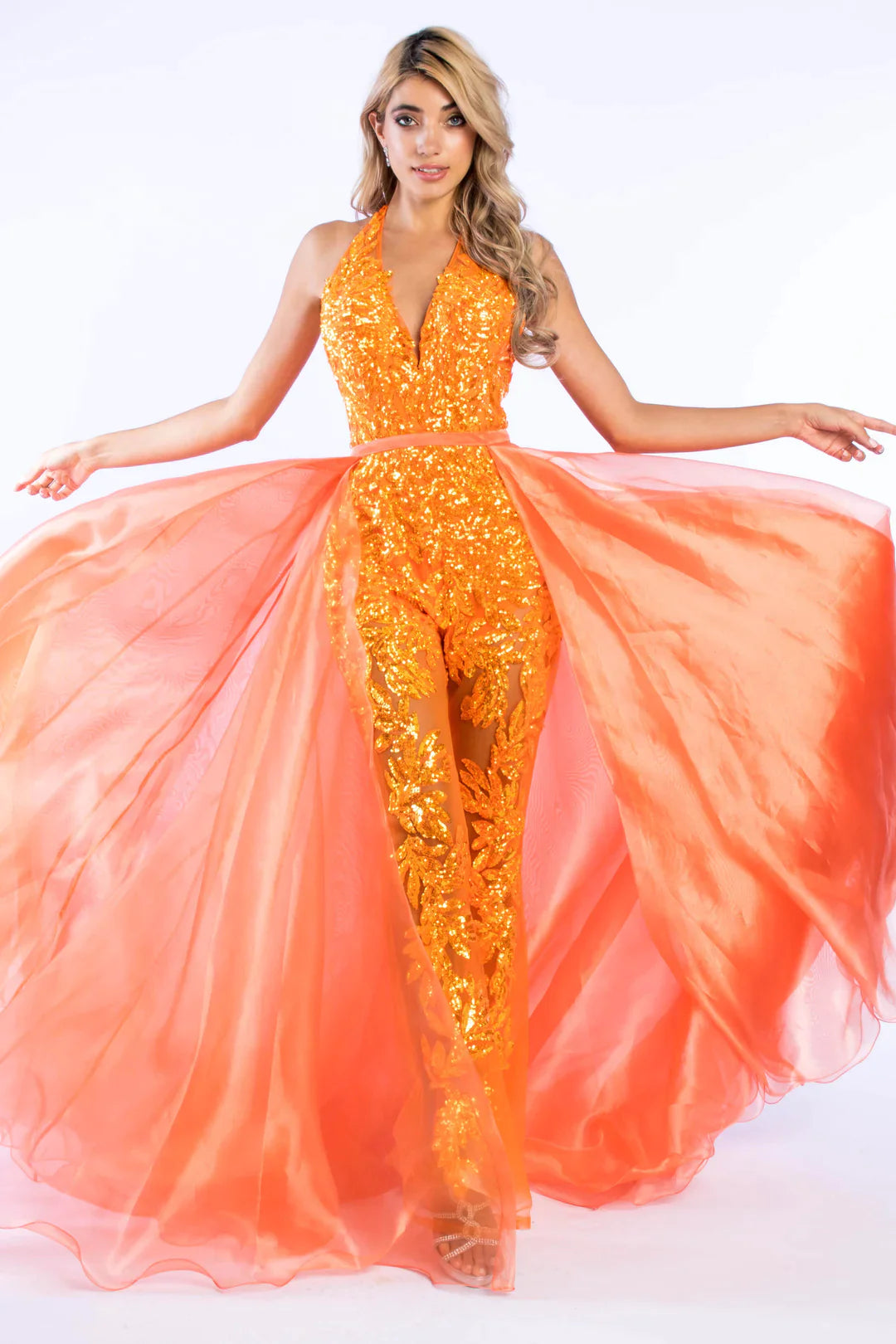 Ava Presley 37381 is crafted with a long, sheer sequin halter jumpsuit, detachable overskirt, V-neck backless design, and a hint of fun fashion. The result is a luxurious, glamorous look perfect for pageants.  Sizes: 0-16  Colors: Royal, Fuchsia, Iridescent Orange