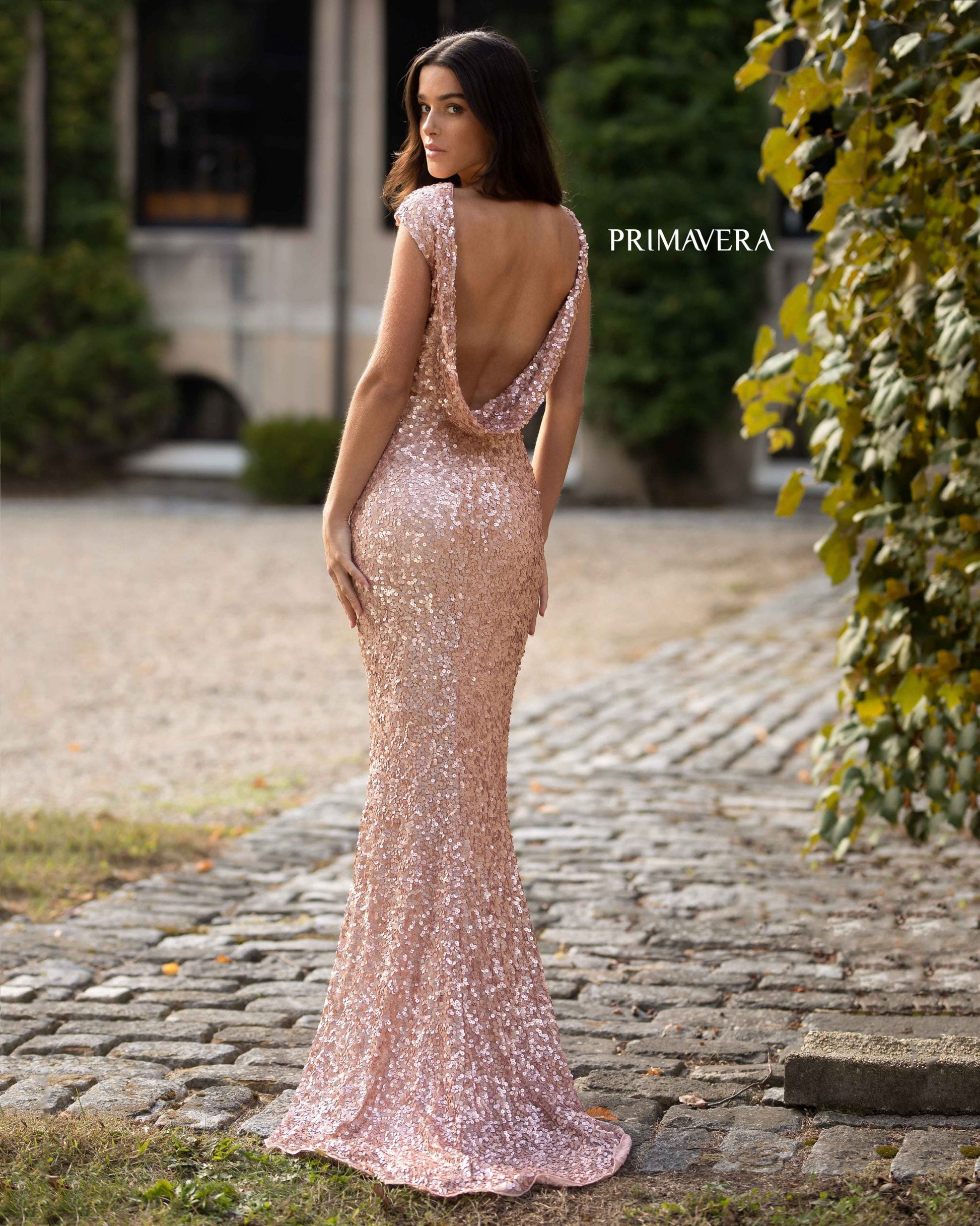 Primavera Couture 3796 This is a beautiful sequined formal evening dress.  The gown has a high neckline and cap sleeves.  The back drapes down to the lower back in a scoop fashion with layers of material that flows as you move.  It is floor length and has a small sweeping train. This is an excellent choice for bridesmaids, mother of the bride or a formal social event.  Available colors: Rose Gold Available sizes: 14