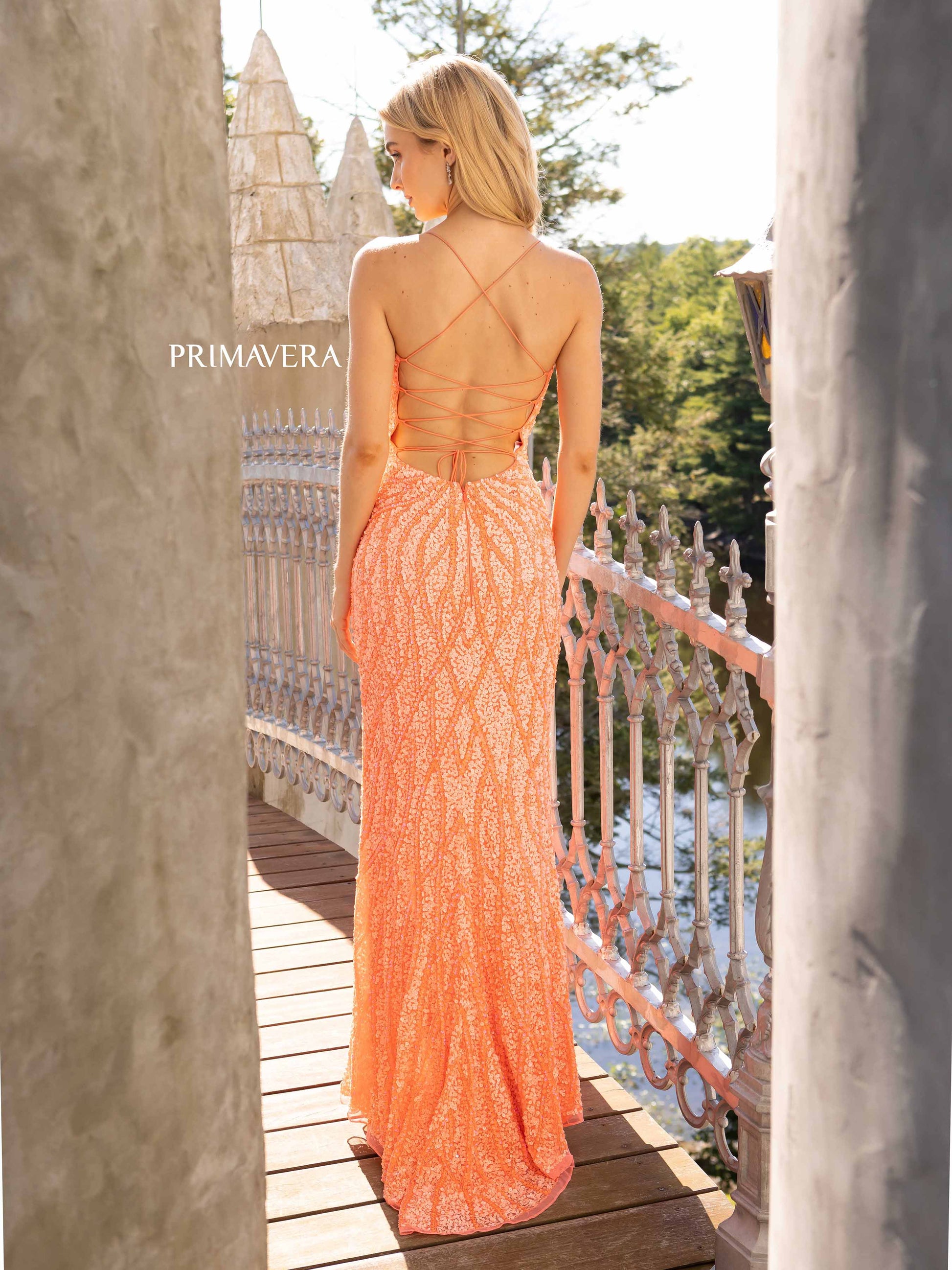 Primavera Couture 3959 This is a coral fully sequined prom dress.  It features a starburst in the front of the dress with waterfall streaming sequins up and down the long length of the dress.  It has a corset open back and a side slit,  Available Size: 2, 10   Available Colors: Coral