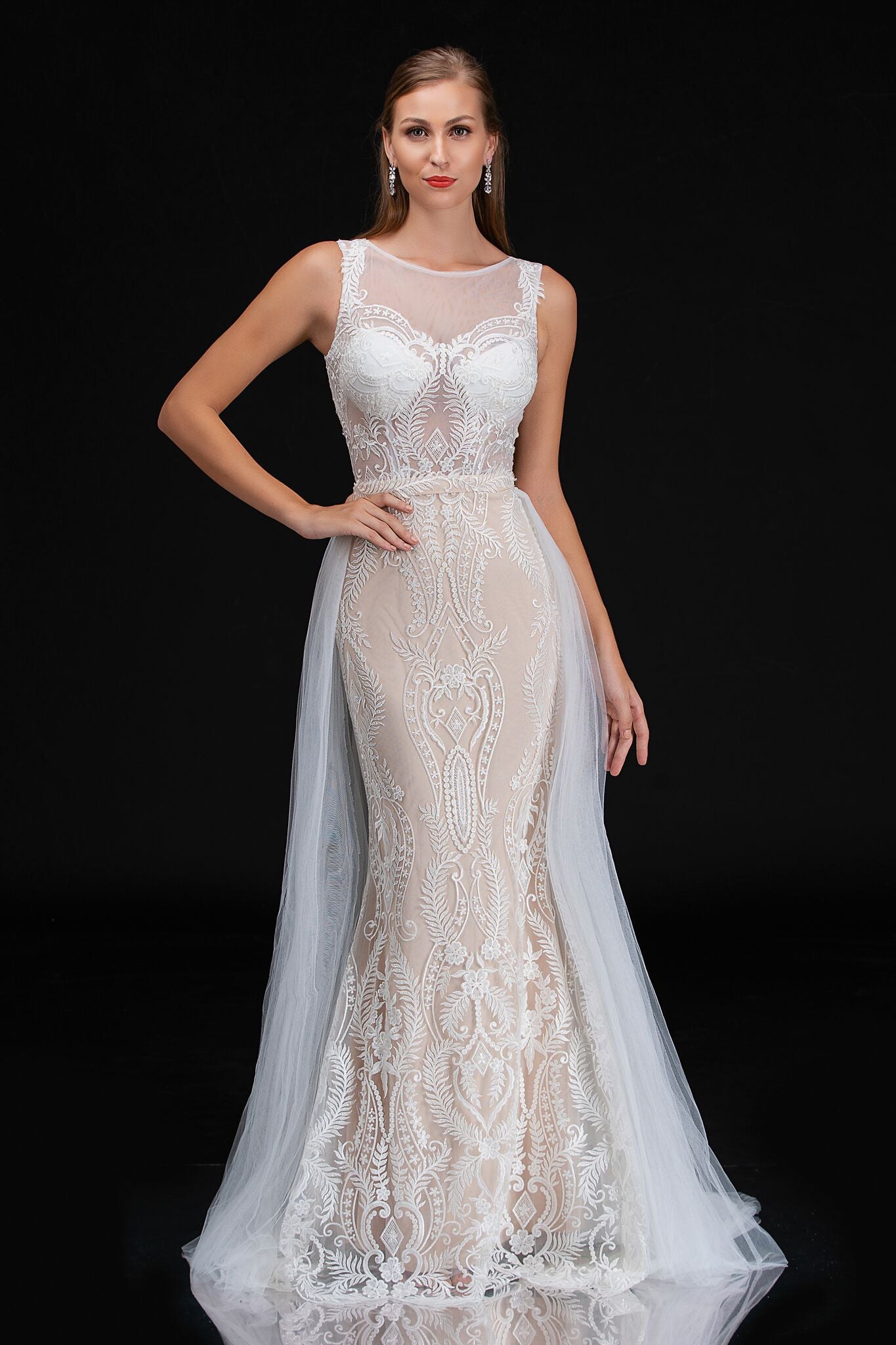 Nina Canacci 4191 is an Ivory & Nude Long Fitted Embroidered Lace Wedding Dress featuring a matching waist belt detachable with a flowing soft tulle overskirt. Open sheer embroidered back. Great destination wedding dress.  Available Sizes: 18  Available Colors: Ivory/Nude 