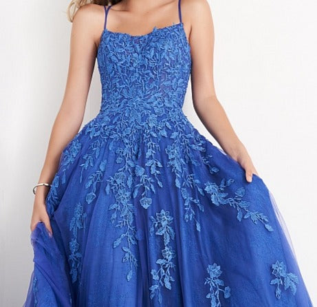 Jovani JVN06644 is a Long Lush Ballgown Prom Dress. This gown features a sheer fitted bodice with a scoop neckline and spaghetti straps. Floral lace appliques Embellish the top and cascade down into the full a line skirt. Open corset lace up tie back with a sweeping train. JVN 06644 Available Sizes: 00,0,2,4,6,8,10,12,14,16,18,20,22,24  Available Colors: Cobalt/Blue, Lilac/White