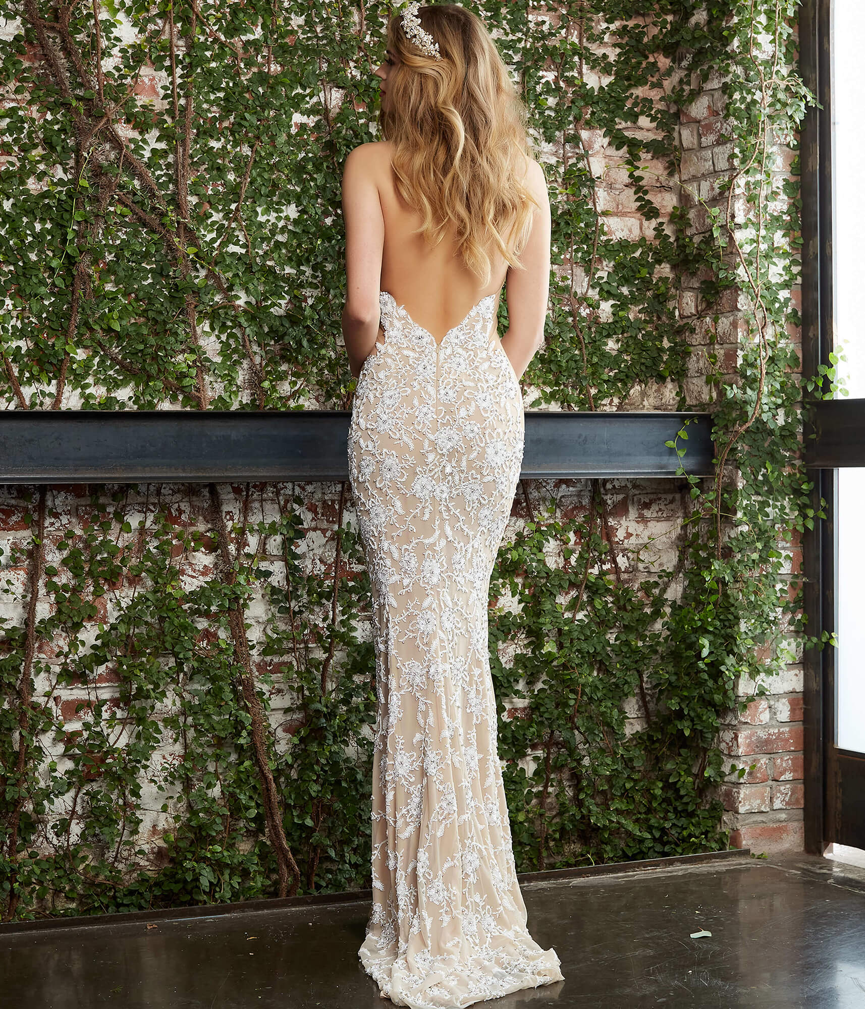 Jovani Bridal S48484 off white and nude wedding gown is encrusted in intricate floral beadwork, with a deep plunging halter neckline and an open back. Mesh side panels contour this fitted bridal dress, finished off with a sweep train. Halter Backless Fitted Beaded V Neck Wedding Dress Couture  Available Sizes: 00-24  Available Colors: Off White/Nude