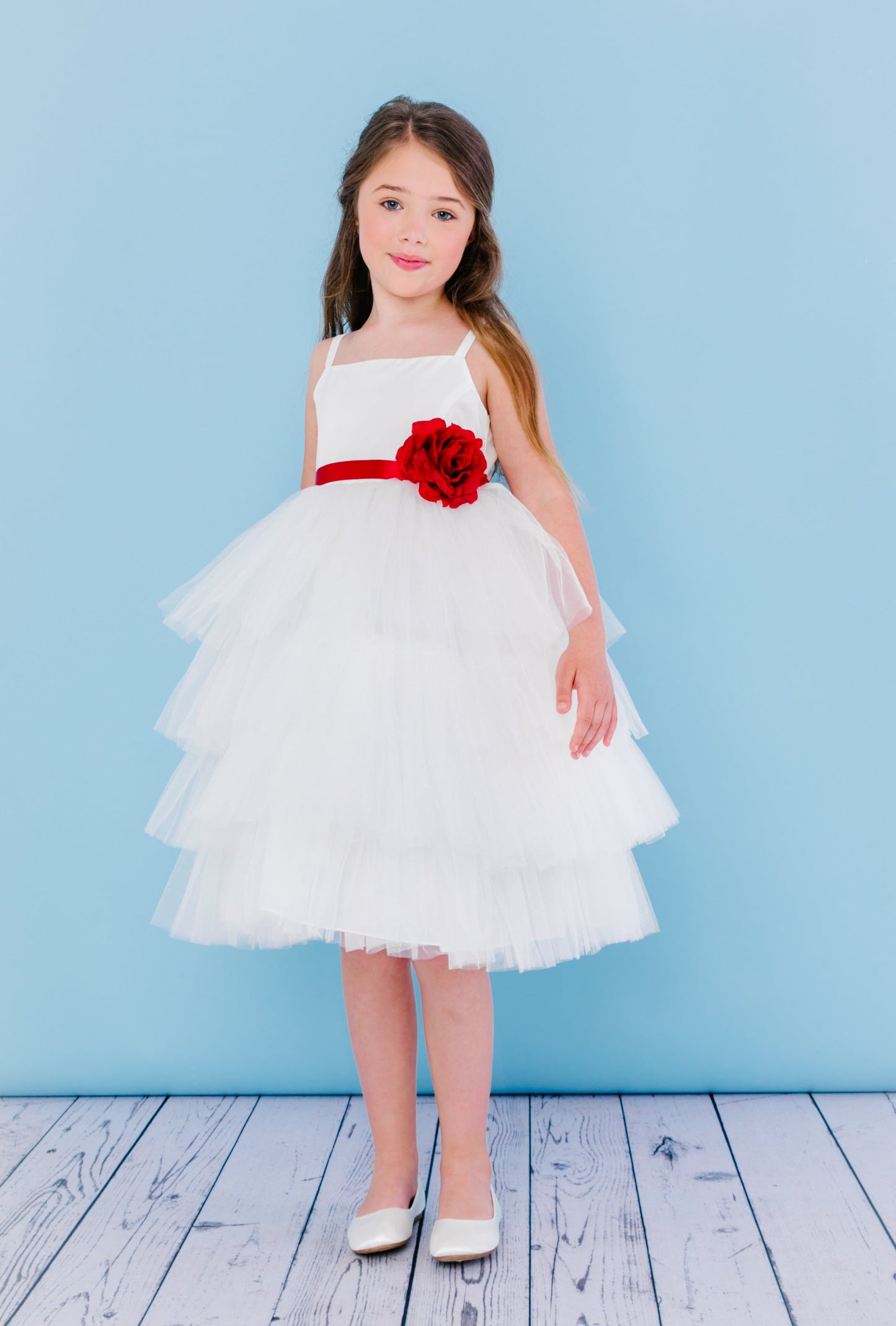 Rosebud Fashions Style 5117 is a spaghetti strap T-length dress. The bodice is satin with a 4 tiered tulle skirt that is accented with a ribbon that ties in the back with a flower. Satin buttons cover the zipper. Great flower girl dress & Formal Party Gown!  Available Sizes: 2,4,6,8,10,12  Available Colors: White, Ivory  Fabric is Satin and Tulle