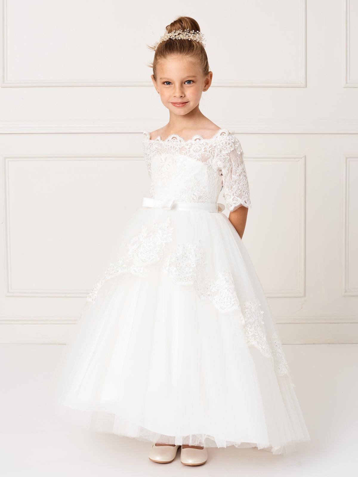 This gorgeous off shoulder dress is perfect for your little girl. The center of the dress has a simple bow at the waist.This dress features a lace peplum skirt with a long train on the back that has beautiful embroidered details. Skirt has additional netting crinoline underneath that can be puffed up if extra fullness is desired. Fully lined, zipper back, and satin sash tie-back.  Available Size: 4  Available Color: Ivory