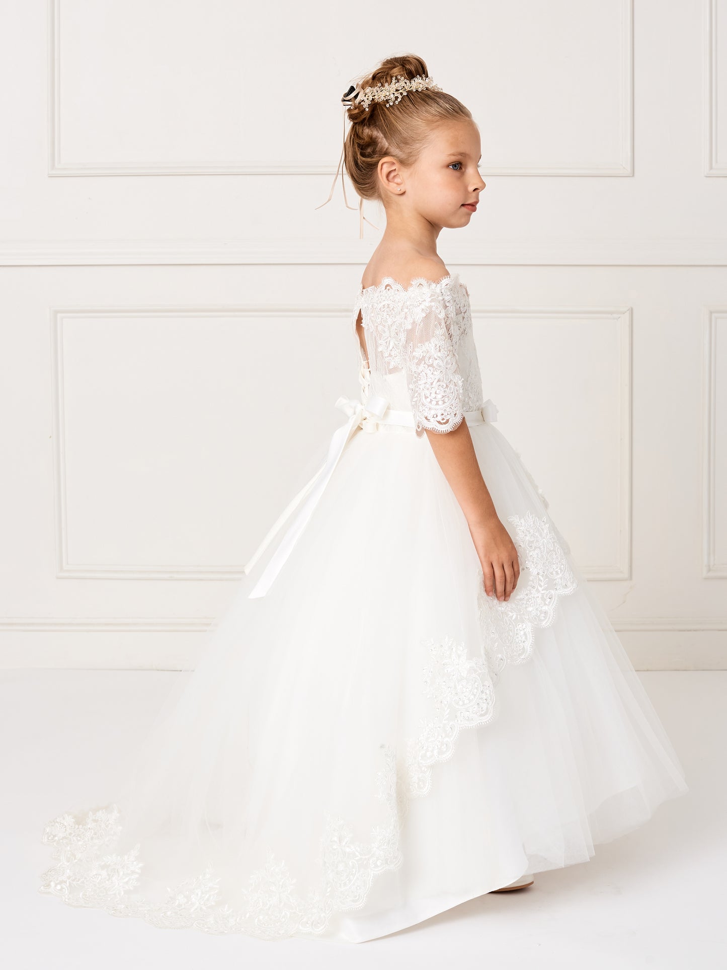 This gorgeous off shoulder dress is perfect for your little girl. The center of the dress has a simple bow at the waist.This dress features a lace peplum skirt with a long train on the back that has beautiful embroidered details. Skirt has additional netting crinoline underneath that can be puffed up if extra fullness is desired. Fully lined, zipper back, and satin sash tie-back.  Available Size: 4  Available Color: Ivory