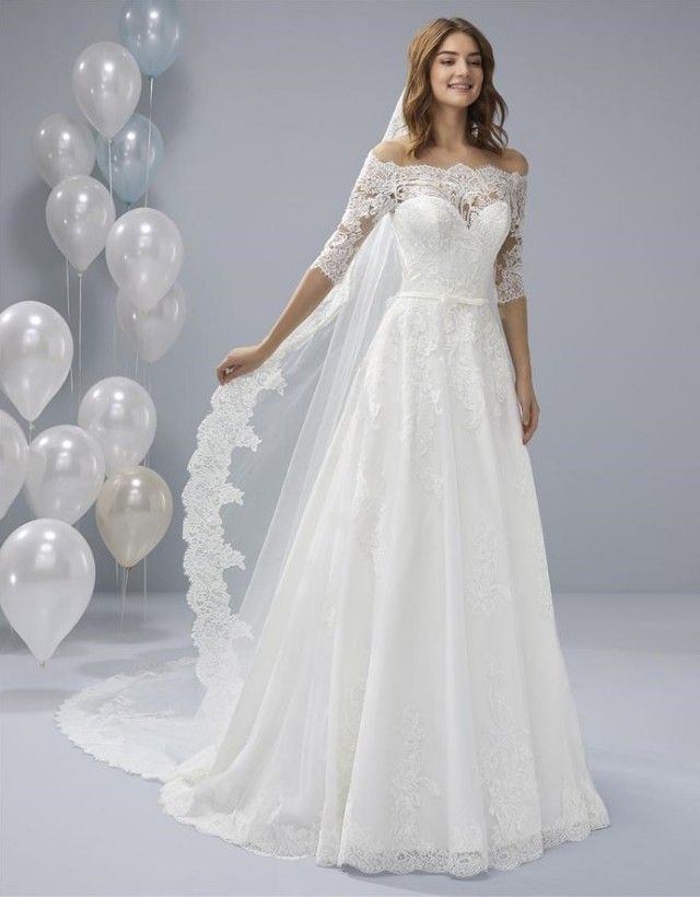 White One OSSA by Pronovias is Probably the wedding dress most little girls have dreamed of; this classic lace tulle gown has the sweetest of necklines with a lace yoke, pretty, lacey school-girl sleeves and a full-blown skirt with a scalloped edge. A Line Lace Ballgown with off the shoulder eyelash three quarter length sheer sleeves. Embroidered Lace Stunning Plus Size Bridal Gown!  Available Size: 28  Available Color: Off White