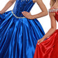 Ritzee Girls 7707 is a long 2020 Satin Ballgown Pageant Dress. This Long Pleated satin ballgown skirt is stage worthy! Sequin Embellished Bodice with boning, Basque Waistline with crystal rhinestone embellishments. off the Shoulder Rhinestone embellished straps leading to an open cutout back with crystal tassels.