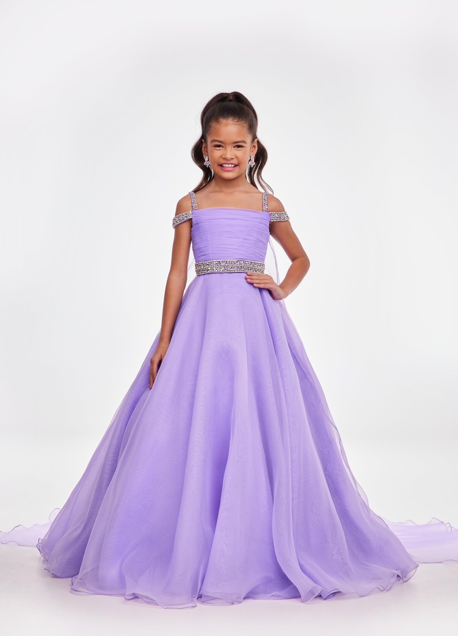 Ashley Lauren Kids 8094 Long off the shoulder A Line Pageant Ball Gown Pageant Dress We are obsessed with this kids evening gown! This organza ball gown features crystal encrusted straps giving way to a ruched bustier. The same crystal detail accents the elegant beaded belt. The look is completed with an A-Line skirt and attached organza cape. Ruched Bustier Crystal Strap &amp; Belt Organza Ball Gown Skirt Organza Cape Available Sizes: 4-14 Available Colors: Neon Orange, Orchid, Hot Pink, Turquoise, Ivory